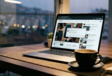 photo of a laptop screen displaying the YouTube Audio Renderer Error message on a dim workspace desk, next to a coffee cup and headphones.